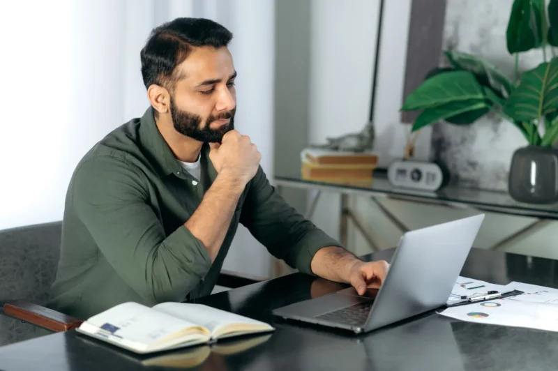 Bearded man sitting at laptop working on property investor tax