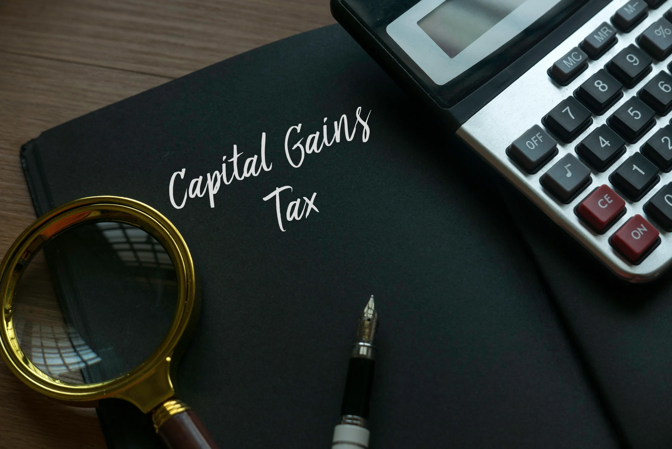 Capital Gains tax in words next to pen, calculator and magnifying glass