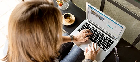 Sole trader sitting with coffee on laptop managing her TaxTank