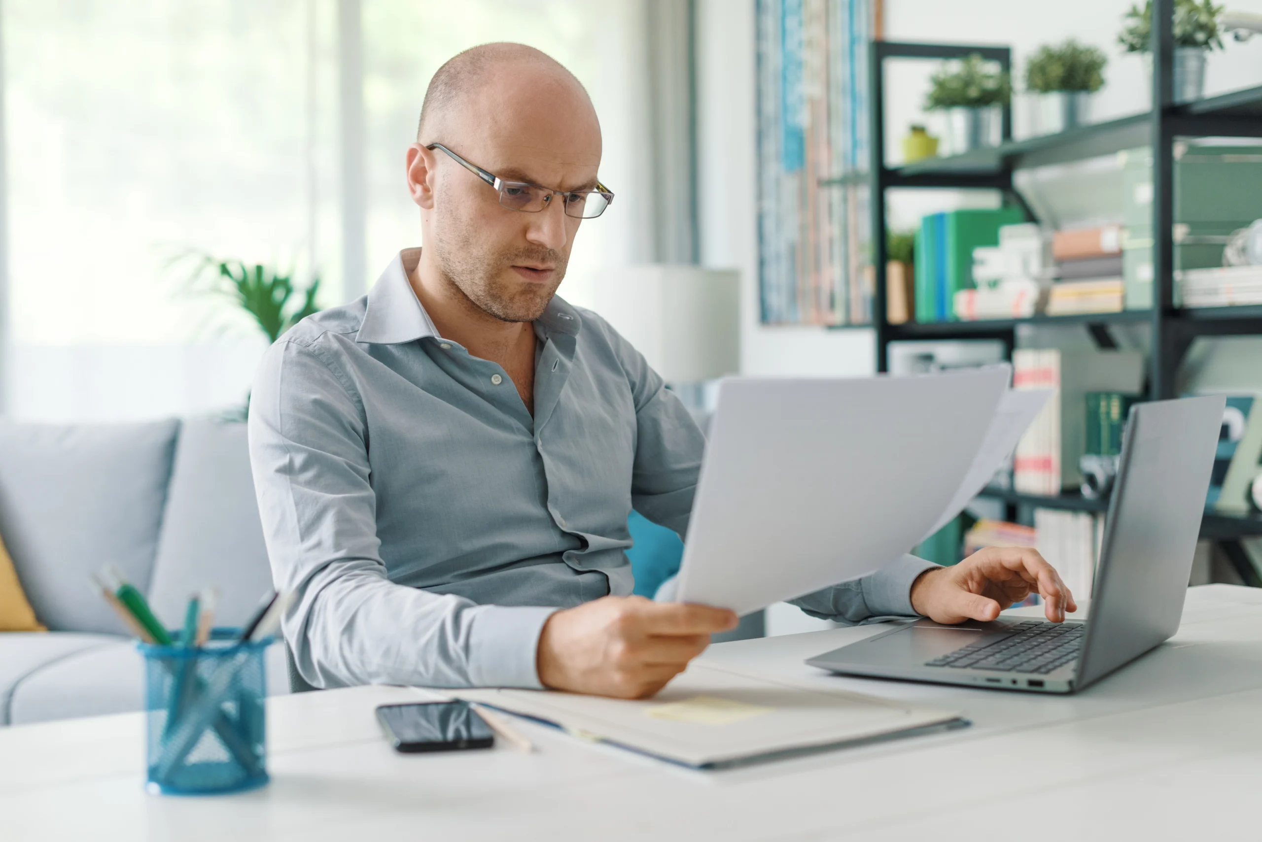 Man wearing glasses and business shirt is checking his documents for overdue tax returns