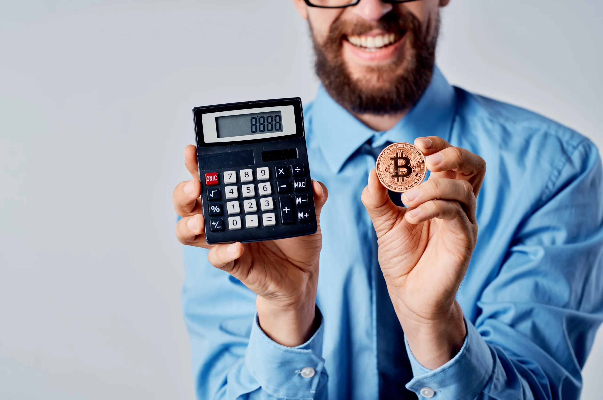 Man with crypto in hand next to calculator illustrating crypto tax calculations