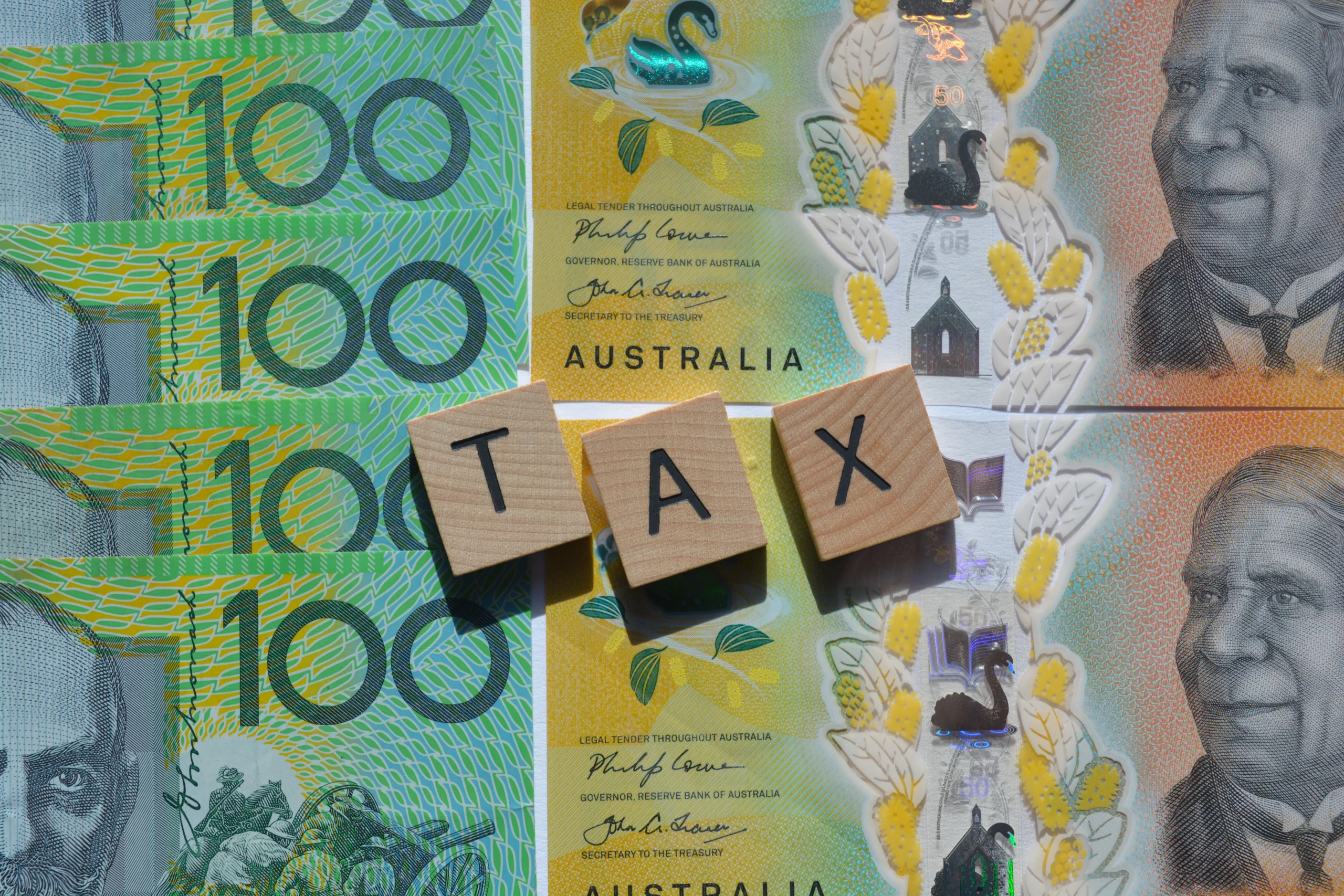 Tax in words over Australian $100 note depicting tax changes