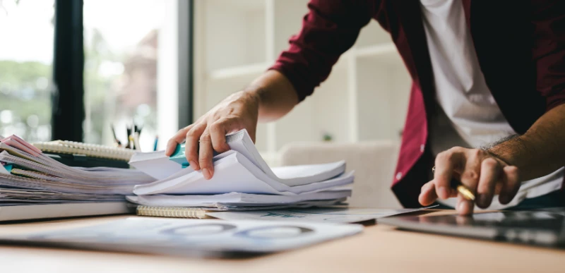 Man sorting through paperwork with calculator