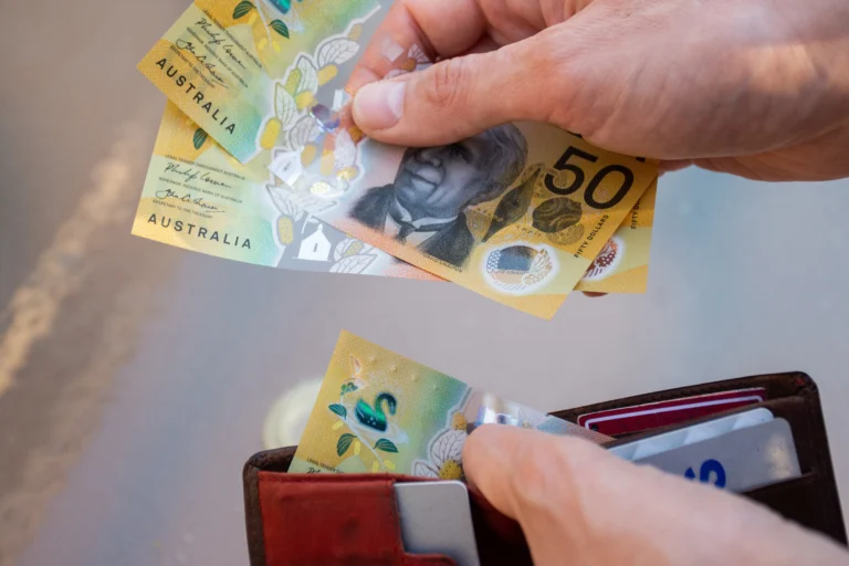 Hands holding wallet with Australian dollars to represent budgeting tips
