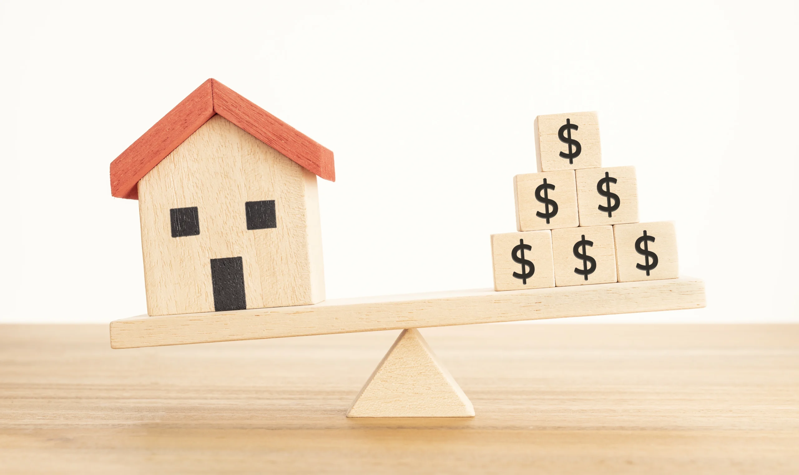 Image of house and dollar blocks on seesaw illustrating negative gearing for investment property