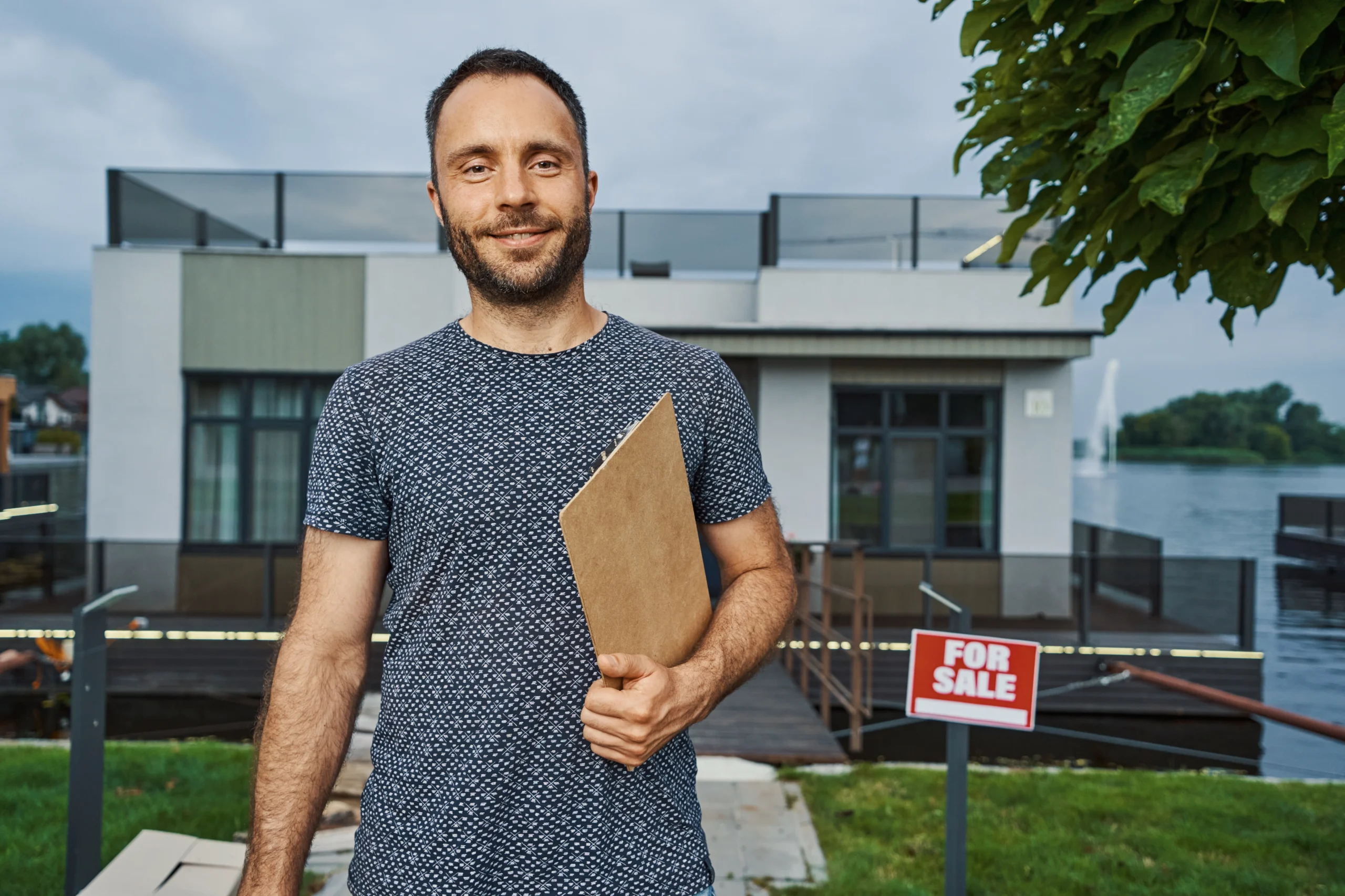 Young man smiling in front of house as he uses negative gearing for property investors as a stragey.